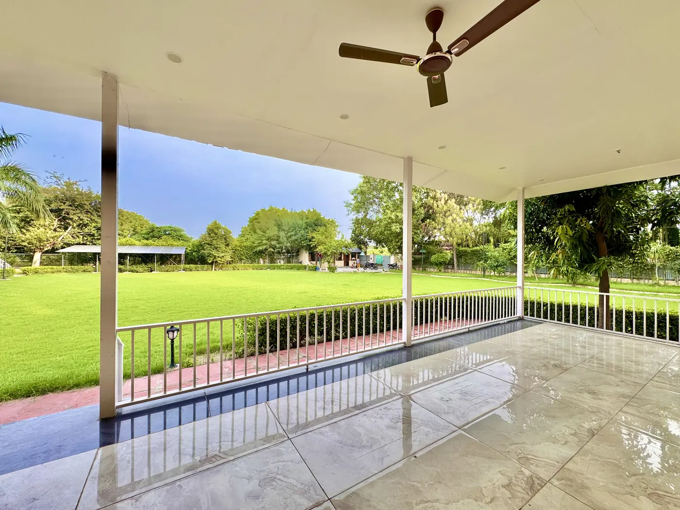 Covered veranda with ceiling fans looking out over the lawn at Mulberry Farm, Noida