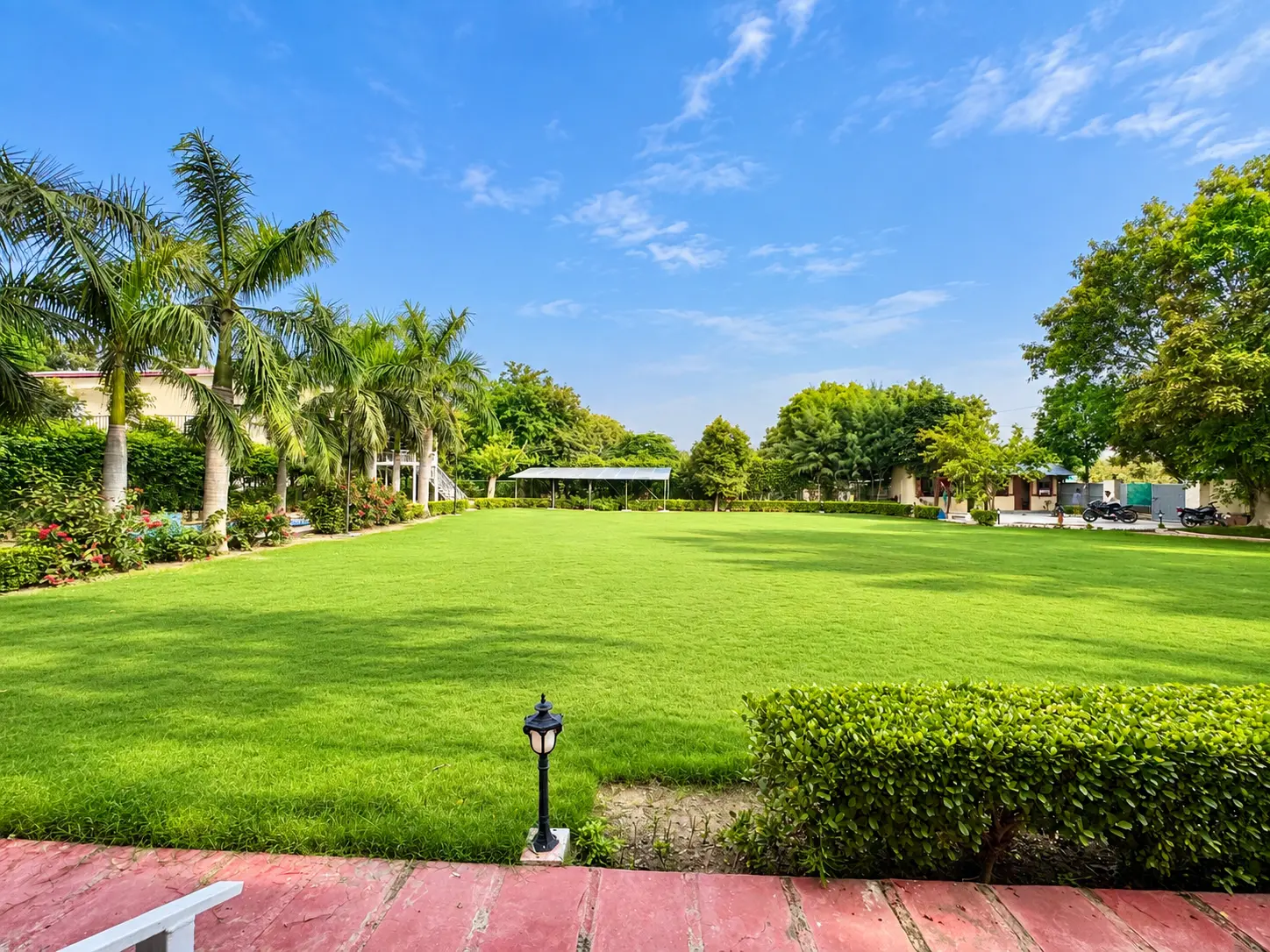 The hedge-lined lawn and the farmhouse at Mulberry Farm, Noida
